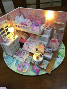 a doll house with furniture and accessories on a table in front of a candle light