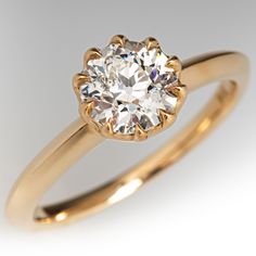 a yellow gold engagement ring with an old cut diamond in the center, on a white background