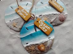 three beach themed ceramic ornaments with name tags and seashells hanging from twine