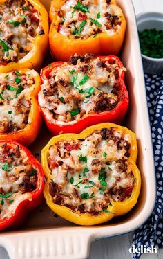 several stuffed peppers in a casserole dish with cheese and seasoning sprinkled on top