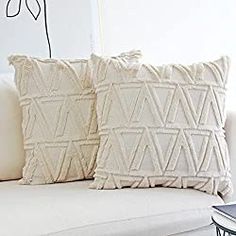 two pillows sitting on top of a white couch