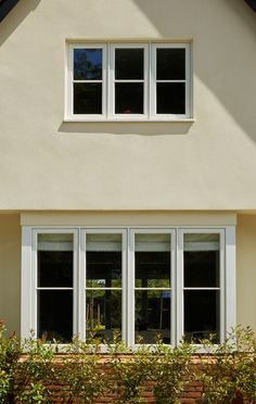 a white house with three windows and bushes in front