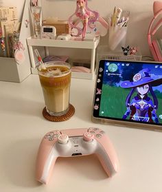 a video game controller sitting next to a cup of coffee and a tablet computer on a desk