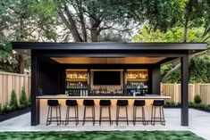 an outdoor bar with several stools in front of it and green grass on the ground