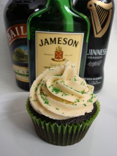 cupcake with frosting next to two bottles of jameson