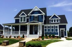 a large blue house with white trim on the front porch and two story, three car garage