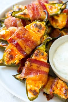 bacon wrapped jalapenos on a plate with ranch dip