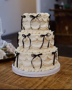 a three tiered wedding cake with black bows on it's edges and white icing