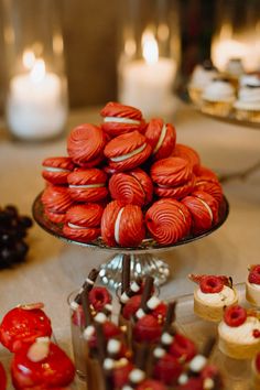 a table topped with lots of red and white cookies next to cupcakes on top of each other