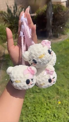 two white teddy bears are held up in the air by a person's hand