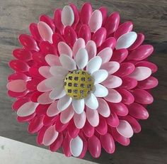 a large pink and white flower sitting on top of a wooden table next to a wall