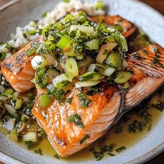 two salmons on a plate with onions and green onion garnish, ready to be eaten