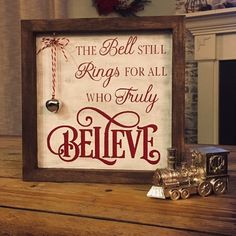 a framed sign with the words believe and a toy train sitting on a wooden table