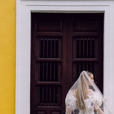 a woman in a wedding dress and veil walking by a door