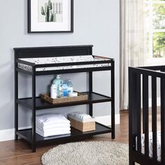 a baby crib in a room with a rug on the floor and pictures above it