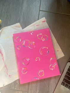 a laptop computer sitting on top of a table next to a pink piece of paper