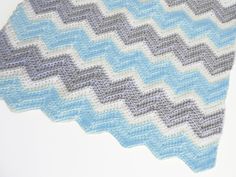 a crocheted blue and gray blanket on top of a white table