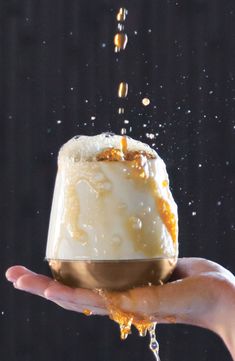 a person holding a cake in their hand with orange and white icing on it