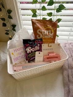 a white basket filled with lots of different types of items next to a potted plant