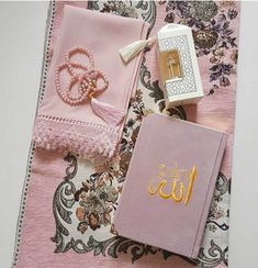 the contents of a pink book are laid out on a floral print tablecloth with tassels and beads