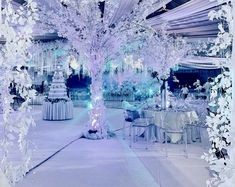 an elaborately decorated wedding reception with white flowers and branches in the centerpieces