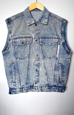 "Vintage 90's blue acid-wash denim vest. Straight collar. Has one half of zippers on each sleeve so it must've been a jacket once. Closes by the front snap buttons. Has two upper side flap pockets and two lower side welt pockets. There are also two large secret pockets on the inside. There is a cool applique front to the left featuring the brand and some national flags. Has two snap-button straps on the side at the bottom hem by which circumference can be adjusted by a choice of two options. Made in Italy. Brand: Utah Jeans Material: 100% cotton Size: tagged size 34DE, which corresponds to size 6US/8UK. For a best fit, please refer to the measurements below. Appr. Measurements (taken with vest lying flat, please double armpit to armpit, waist and bottom hem): shoulder seam to shoulder seam Cheap Y2k Denim Vest For Summer, Cheap Fitted Vintage Denim Jacket, Trendy Washed Denim Vest, Trendy Medium Wash Vest, Fitted Denim Vest With Washed Detail, Summer Washed Denim Jacket For Streetwear, Summer Streetwear Washed Denim Jacket, Fitted Medium Wash Vest, Trendy Fitted Vest For Streetwear