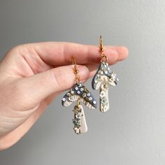 a person holding two pairs of earrings in their hand, one has a giraffe charm on it