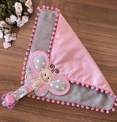 a pink and gray baby's blanket with a teddy bear on the front is laying next to flowers