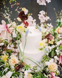 a white wedding cake surrounded by flowers and greenery