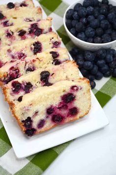 slices of blueberry bread on a white plate next to fresh berries and a bowl of blueberries