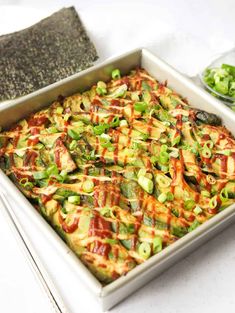 a casserole dish with vegetables and sauce in it on a white tablecloth