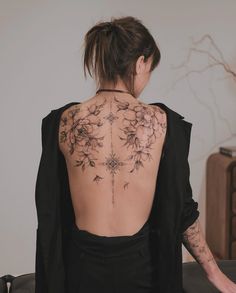 the back of a woman's body with tattoos on her upper and lower back