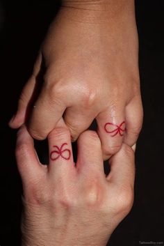 two hands holding each other with red ink on their fingers and the word love written in them