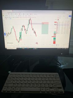 a computer monitor with a keyboard and mouse on it's side, in front of the monitor is a stock chart