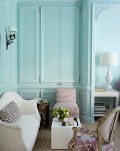 a living room with blue walls and white furniture in the corner, along with two chairs