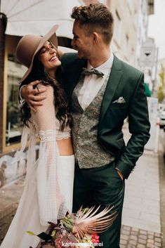 a man in a suit and tie standing next to a woman wearing a wedding dress