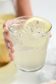 a person holding a glass filled with ice and lemon