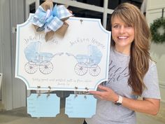 a woman holding up a sign with a baby carriage on it and a blue bow