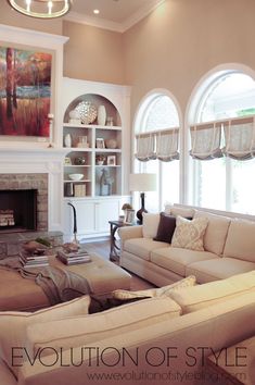 a living room filled with furniture and a fire place in front of a window covered wall