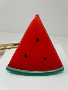 a watermelon slice sitting on top of a piece of paper next to a pen