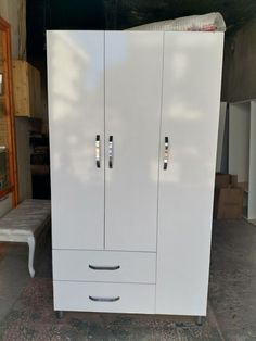 a tall white cabinet with two doors on the front and one door open, in a garage