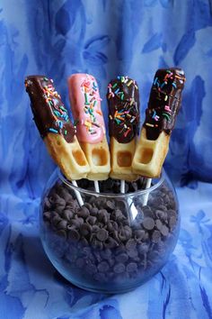 chocolate covered waffles with sprinkles in a glass bowl on a blue background