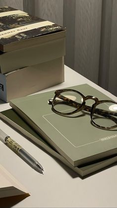 a pair of glasses sitting on top of a book next to a pen and eyeglasses