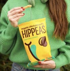 a woman wearing headphones and holding a bag of hip peas with the word'organic chickpeas'printed on it