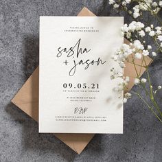 the wedding stationery is laid out on top of an envelope and some flowers are placed next to it