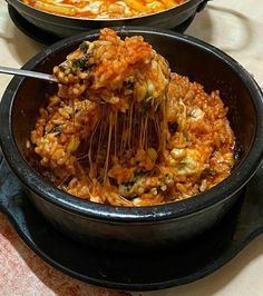 two black bowls filled with food on top of a table