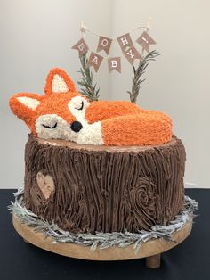 a cake made to look like a fox sleeping on top of a tree stump with decorations around it