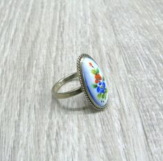 "Finift enameled jewelry, USSR vintage ring with enamel painting, retro statement ring for woman, her anniversary gift, Red poppy and blue cornflower ring. This Russian hand painted enamel ring features red Poppy flower along with blue cornflower, surrounded with green leaves on baby blue background Size: 6 1/2 ( US and Canada ), N, O 1/2, Q( UK and Australia ), 17, 17 1/4, 18 ( European ). The enamel painted oval cabochon is 10 mm wide and 22 mm long. It is set in silver tone metal cast with a Antique Enamel Ring As A Gift, Vintage Blue Enamel Rings, Vintage Enamel Anniversary Ring, Elegant Hand Painted Enamel Ring As A Gift, Elegant Hand Painted Enamel Ring Perfect For Gifting, Elegant Hand Painted Enamel Ring For Gift, Vintage Enamel Ring For Anniversary, Handmade Enamel Vintage Rings, Handmade Vintage Style Enamel Ring