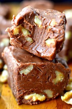 three pieces of chocolate fudge on top of a wooden cutting board with walnuts