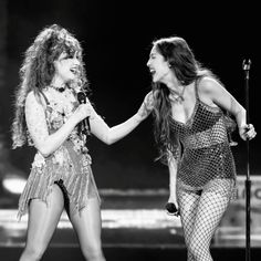 two women in fishnet outfits on stage with one holding the other's hand